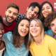 Group of seven smiling, happy individuals against a red background.